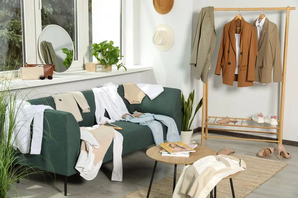 Messy pile of clothes on sofa and shoes in living room