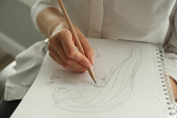 Woman drawing girl's portrait with pencil in notepad, closeup