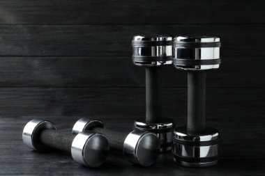 Set of metal dumbbells on black wooden table