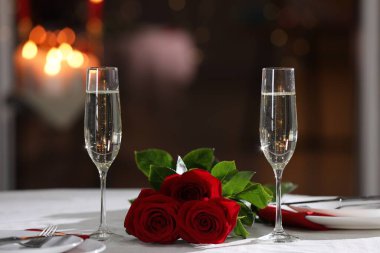 Romantik yemek masası, şampanya bardakları ve restoranda kırmızı güller.