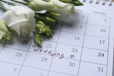 Calendar with date reminder about Wedding Day and flowers, closeup