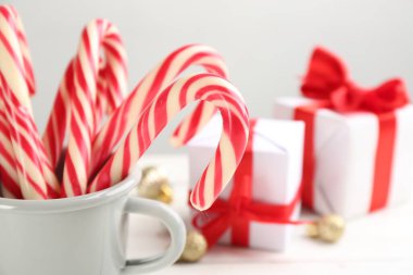 Many sweet candy canes in cup on table, closeup. Traditional Christmas treat