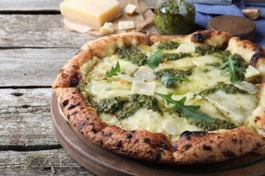 Ahşap masada pesto, peynir ve roka ile nefis pizza, yakın plan.