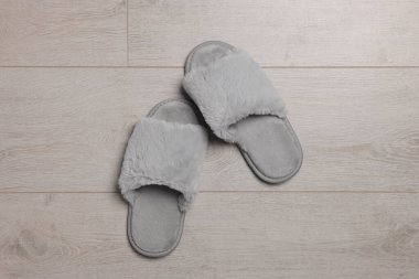 Pair of soft grey slippers on wooden floor, top view