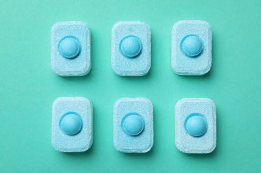 Water softener tablets on turquoise background, flat lay