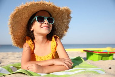 Güneşli bir günde kumsalda uzanmış tatlı küçük bir çocuk.