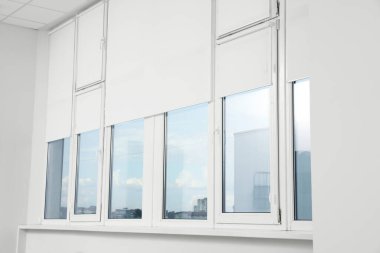 Plastic windows with white roller blinds indoors