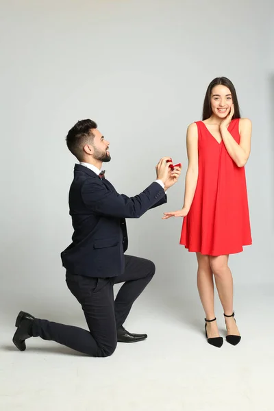婚約指輪を持つ男作る結婚提案へ彼女にライトグレーの背景 — ストック写真