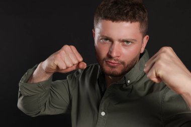 Young man ready to fight on black background