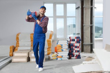 Construction worker with new building materials in room prepared for renovation