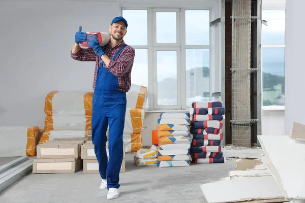 Construction worker with new building materials in room prepared for renovation