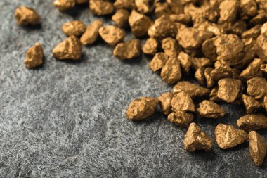 Pile of gold nuggets on grey table, space for text