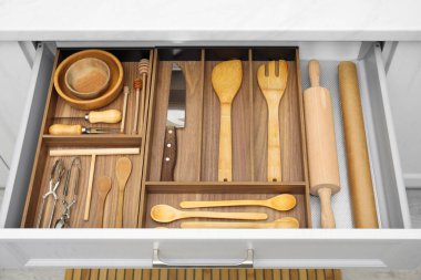 Open drawer of kitchen cabinet with different utensils, above view