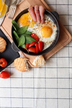Masada servis edilen ıspanaklı, domatesli ve jambonlu leziz sahanda yumurta. Metin için boşluk