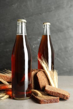 Gri masada bir şişe taze kvass, dikenler ve ekmek.