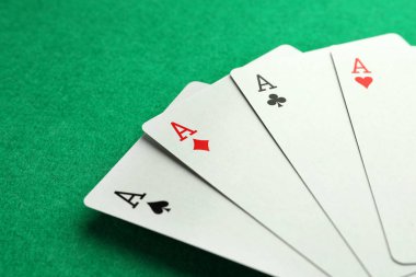 Four aces playing cards on green table, closeup. Poker game