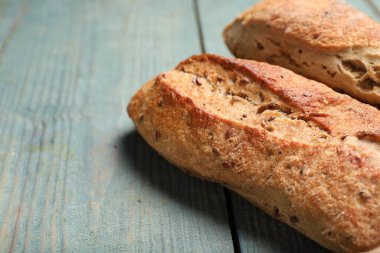Tasty buckwheat baguettes on light blue wooden table, closeup. Space for text