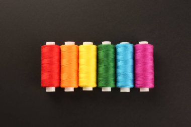 Siyah arkaplan üzerinde farklı renkli dikiş iplikleri, düz yatıyordu