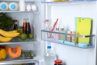 Storage of cosmetics in refrigerator door bin next to groceries