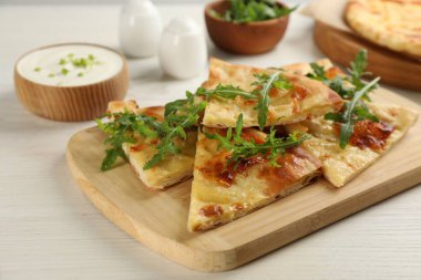 Beyaz ahşap masada servis edilen peynirli lezzetli khachapuri.