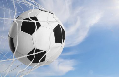 Soccer ball in net against blue sky