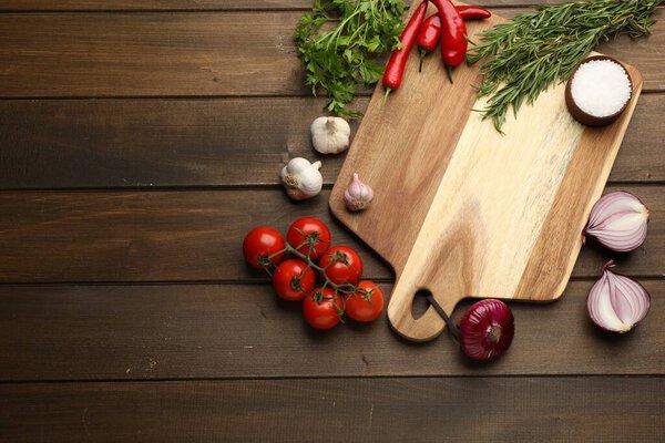 Cutting board and vegetables on wooden table, flat lay with space for text. Cooking utensil
