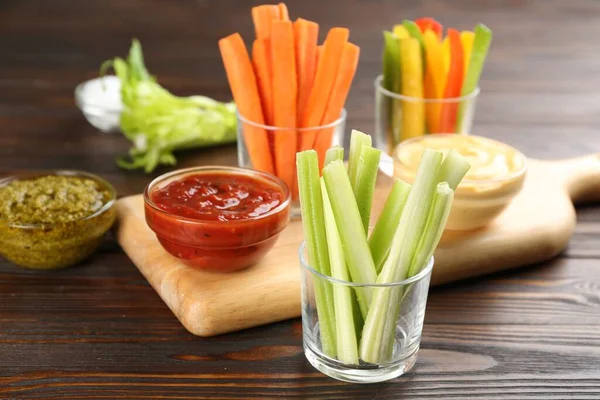 Celery sticks in glass bowl and dip sauce on wooden table