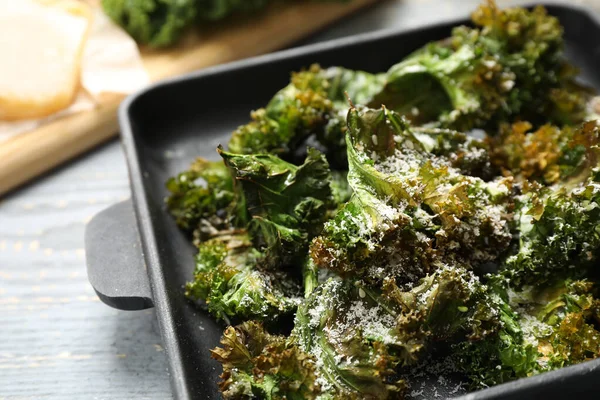 Tasty baked kale chips on grey table, closeup