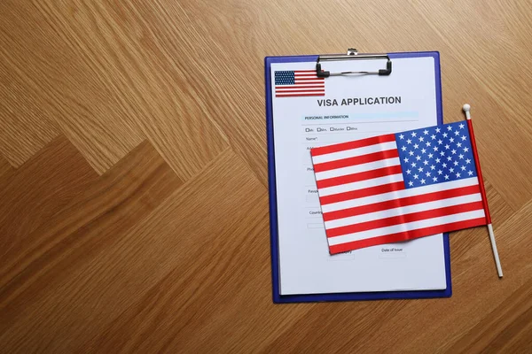 Visa application form and small American flag on table, flat lay. Space for text