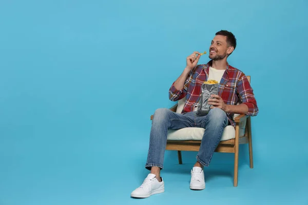 Handsome Man Eating Potato Chips Light Blue Background Space Text — Photo