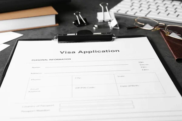 Visa application form for immigration and stationery on grey table, closeup