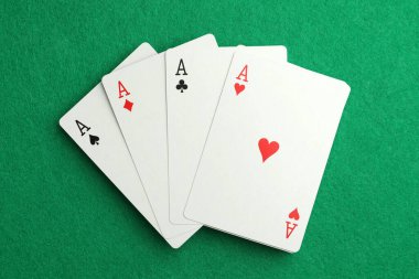 Four aces playing cards on green table, top view. Poker game