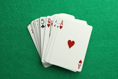 Deck of playing cards on green table, top view. Poker game