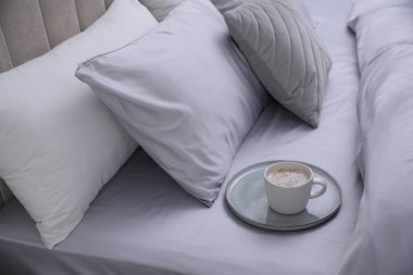 Yumuşak ipek çarşaflı yatakta bir fincan kahve.
