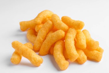 Heap of tasty cheesy corn puffs on white background, closeup