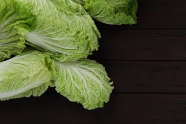 Fresh ripe Chinese cabbages on dark wooden table, fat lay. Space for text