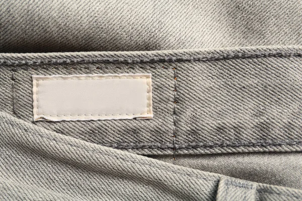 Blank clothing label on grey jeans, top view