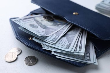 Dollar banknotes in wallet and coins on white table, closeup. Money exchange