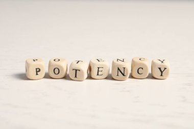 Wooden cubes with word Potency on white table, closeup