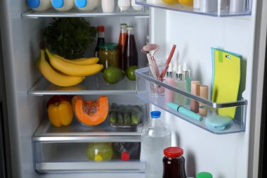 Storage of cosmetics and tools in refrigerator door bin next to groceries