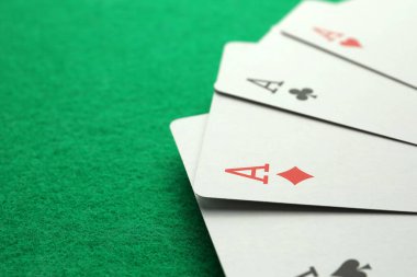 Four aces playing cards on green table. Space for text