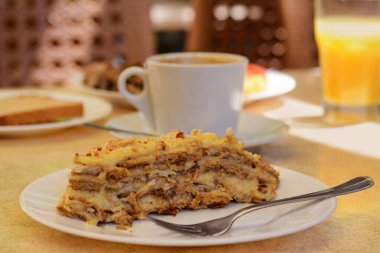 Piece of delicious cake and coffee on beige table in cafe, closeup