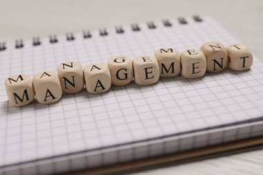 Word Management made of wooden cubes and notebook on white table, closeup