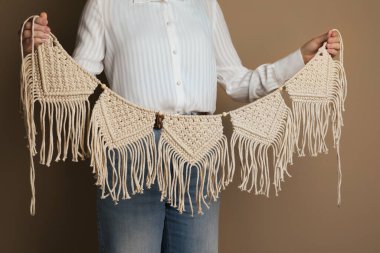 Woman holding large macrame on beige background, closeup