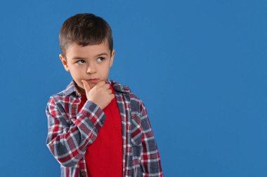 Mavi arka planda düşünceli küçük çocuk, mesaj için yer var.