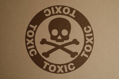 Hazard warning sign (skull-and-crossbones symbol and word TOXIC) on kraft paper, top view