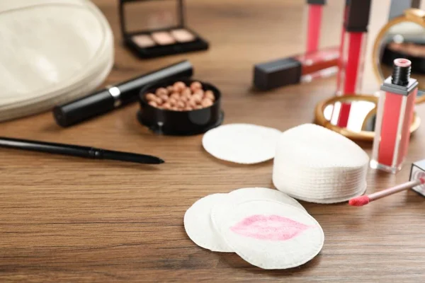 Dirty cotton pads and cosmetic products on wooden table