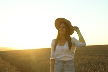 Beautiful young woman in ripe wheat field on sunny day, space for text