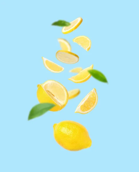 Fresh Ripe Lemons Green Leaves Falling Light Blue Background — kuvapankkivalokuva