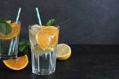 Soda ve nane aromalı lezzetli portakallı limonata, siyah masada, mesaj için yer var. Taze yaz kokteyli.